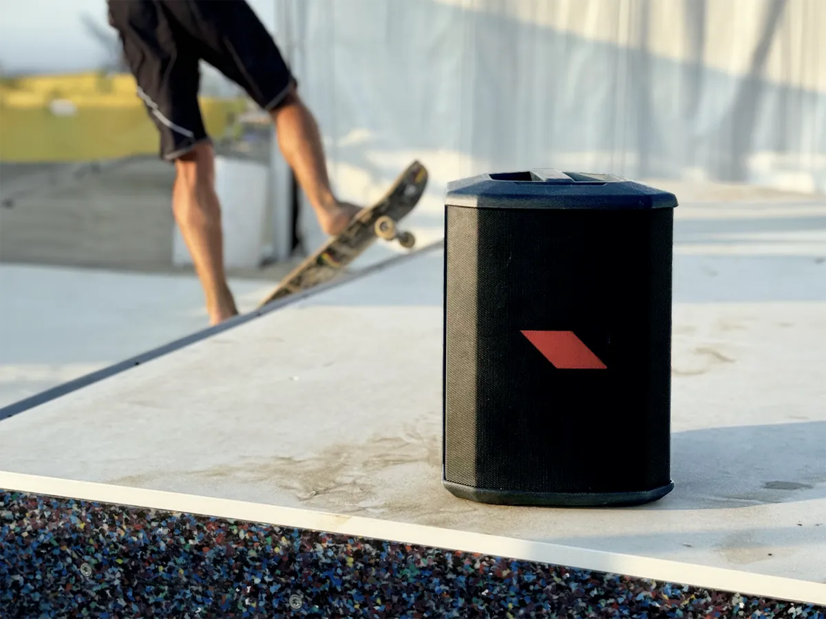 A PROEL portable speaker standing at the edge of a skate ramp, a skater behind it