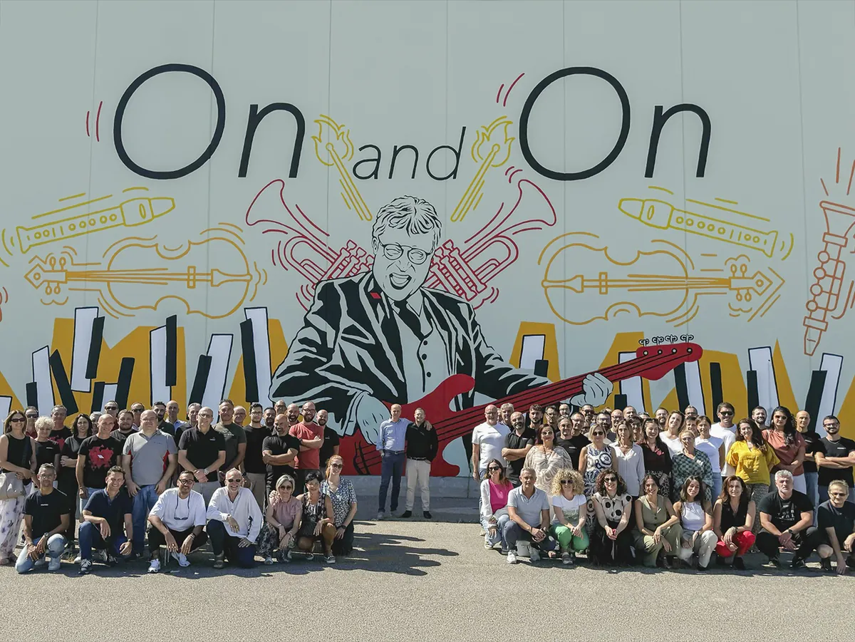 The PROEL team gathered together in front of the On and On mural outside the factory