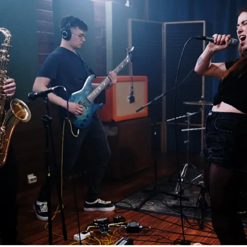 A band rehearsing: saxophone, electric guitar and a singer at the microphone